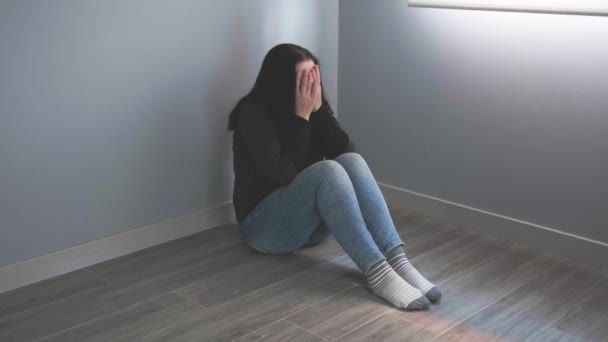 Depressieve vrouw met problemen om haar gezicht te bedekken zittend op de vloer - Video