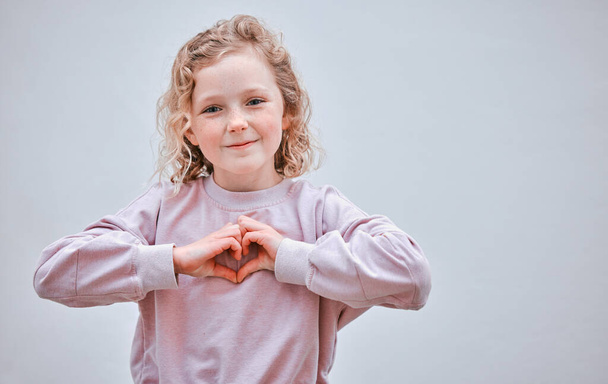Keep your heart pure from the start. Studio shot of a little girl making a heart shaped gesture against a grey background - Fotoğraf, Görsel