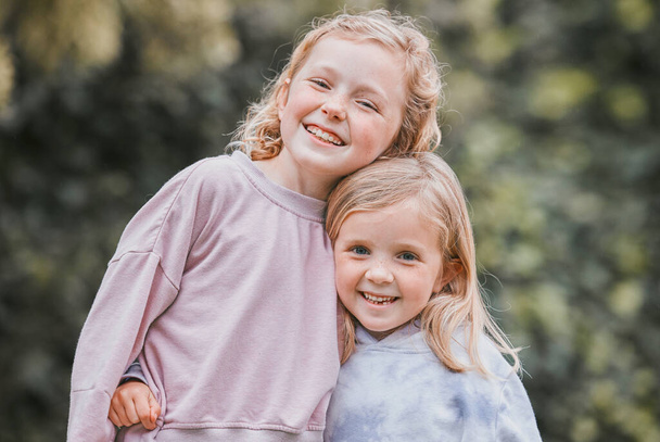 Alles wat je nodig hebt is liefde, en een zusje. twee schattige kleine meisjes hebben plezier in een tuin - Foto, afbeelding