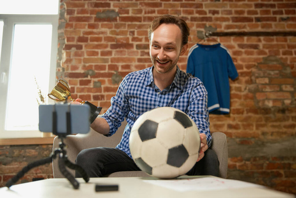 Joy of winning your favorite team. Happy man, soccer fan recording vlog about last football match and shares his opinion on the strategy of the game. Sport, hobby and leisure concept. - Foto, Imagen