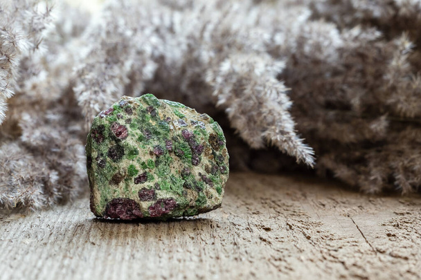 Eklogitowa skała zawierająca zielony piroksen i czerwony granat lub pylin na drewnianym naturalnym tle z przestrzenią do kopiowania - Zdjęcie, obraz