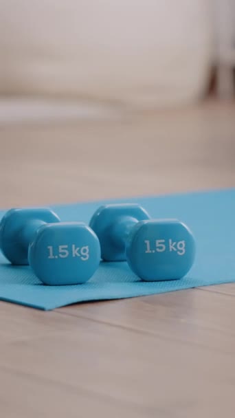 Vertical video: Close up of dumbbells used to train arms muscles at home. Nobody in room with lifting weights placed on floor yoga mat. Empty space with fitness and training equipment. Sporty activity - Footage, Video