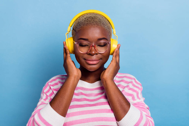 Photo of cheerful cute nice young attractive gorgeous woman holding her headphones listen music isolated on blue color background. - Foto, imagen