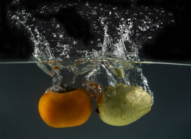 Frutas que entran en el agua con salpicaduras por todas partes - concepto de comer fresco. - Foto, Imagen
