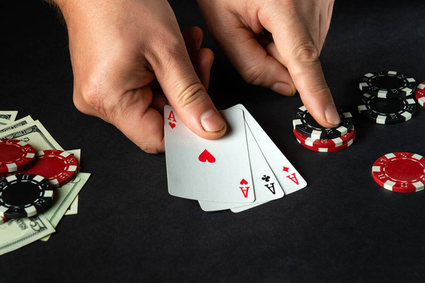 Il giocatore mette carte da gioco con una combinazione vincente di tre di un genere o impostare nel gioco del poker su un tavolo nero con fiches e denaro. - Foto, immagini