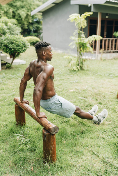 Black man doing triceps dip exercise on a bench.. High quality photo - Foto, afbeelding