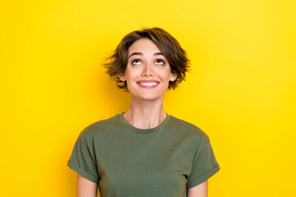 Portrait of glad impressed woman with bob hairdo dressed khaki t-shirt staring look empty space isolated on yellow color background. - Фото, зображення