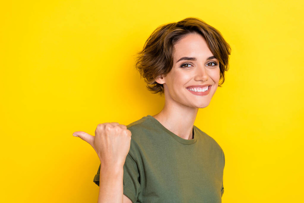 Portrait of gorgeous pretty woman with bob hairdo dressed khaki t-shirt directing empty space poster isolated on yellow color background. - Φωτογραφία, εικόνα