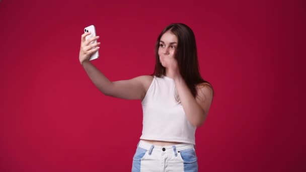4k video van tiener vrouw nemen selfie geïsoleerd over rode achtergrond. Begrip beïnvloeders. - Video