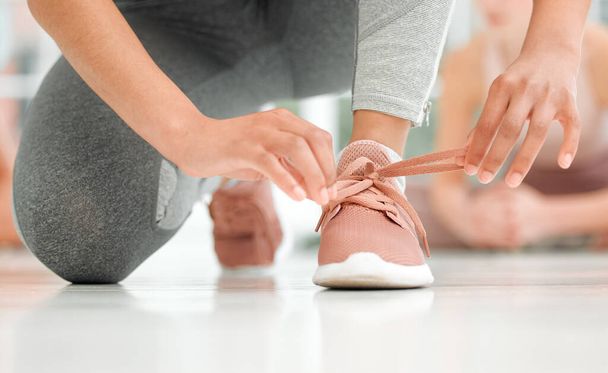 Put your perseverance to work. an unrecognizable woman tying her shoelaces - 写真・画像