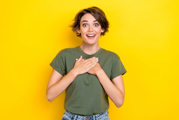 Photo of adorable lovely girl with bob hairstyle wear khaki t-shirt arms on chest impressed staring isolated on yellow color background. - Foto, Imagen