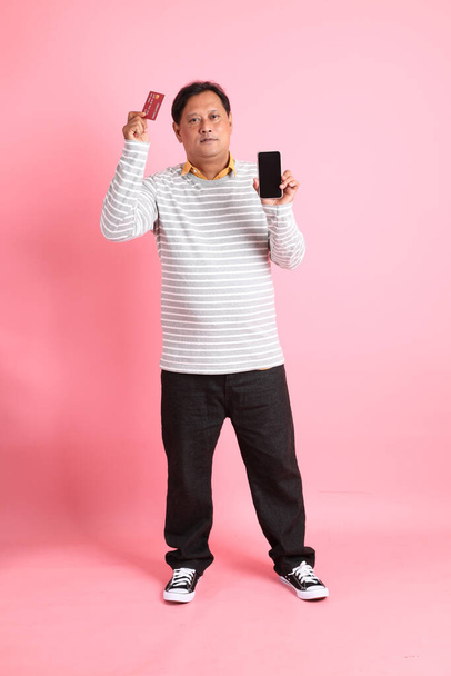 Os anos 40 adulto acima do peso asiático homem de pé sobre o fundo rosa. - Foto, Imagem