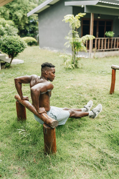Black man doing triceps dip exercise on a bench.. High quality photo - Photo, image