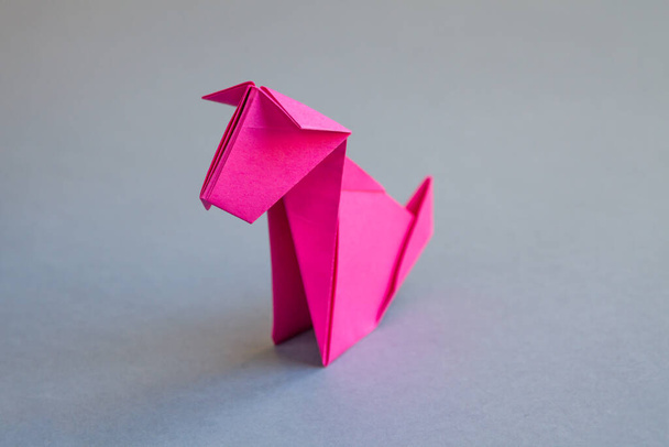 Pink paper dog origami isolated on a blank grey background. - Valokuva, kuva
