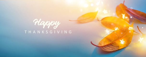 Kunst gelukkig Thanksgiving spandoek ontwerp. herfst gele bladeren en feestelijke verlichting op een blauwe achtergrond - Foto, afbeelding