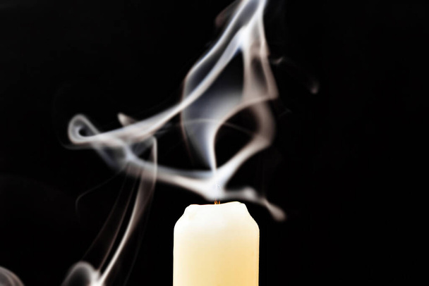 Gray smoke from an extinguished candle develops on a black background. - Photo, Image