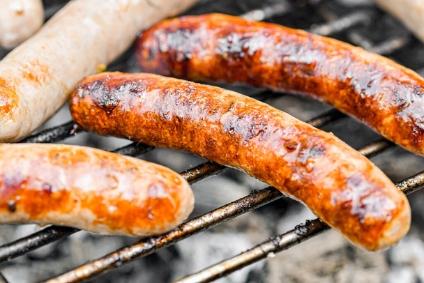 Marinated grilled sausages are fried on a fire. - Фото, зображення