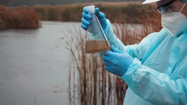 Genç bilim adamı biyolog su ve toprağın kirliliğini analiz ediyor. Uzmanlık için matarası olan bir adam. Çevresel Kirlilik Suyu Numunesi Sorunları. Yüksek kalite 4k görüntü - Video, Çekim