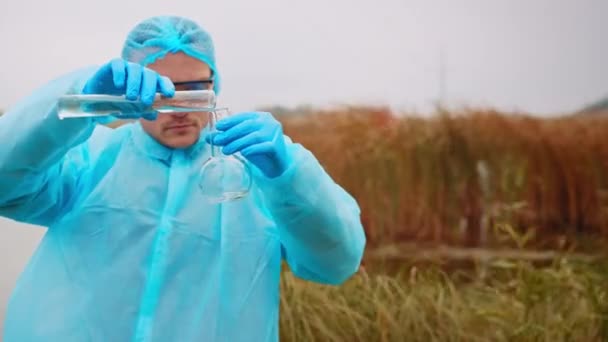 Lavoro dello scienziato ecologico, l'uomo versa i campioni di acqua dalla provetta nella fibbia per ulteriori studi sulla contaminazione, biologo che analizza il test dell'acqua. Filmati 4k di alta qualità - Filmati, video