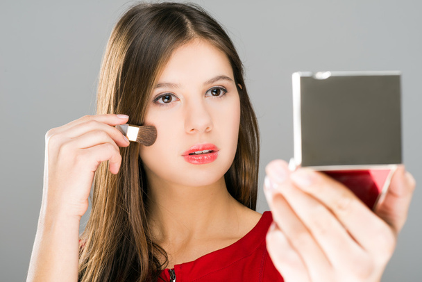 Kobieta stosowania makijażu, patrząc w lustro - Zdjęcie, obraz