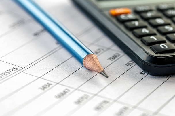 Calculadora y lápiz de primer plano sobre un fondo borroso, el concepto de cálculos de impuestos y finanzas. - Foto, imagen