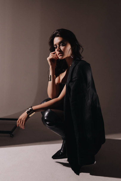 fashion outdoor photo of beautiful woman with dark hair in elegant black lingerie and jacket posing in studio - Φωτογραφία, εικόνα