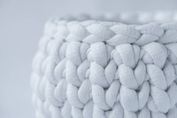 close-up of crocheted white basket, stuff organizer, crochet baskets bottom, pattern for crocheting, nature-friendly sustainable handicraft business, cute interior items. Space for your text - Фото, изображение