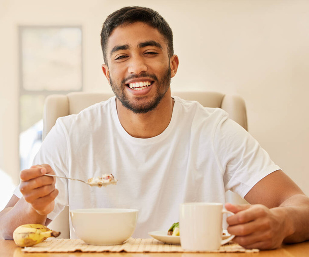 Meine Energie beziehe ich aus dem Frühstück. ein hübscher junger Mann sitzt allein und frühstückt zu Hause - Foto, Bild