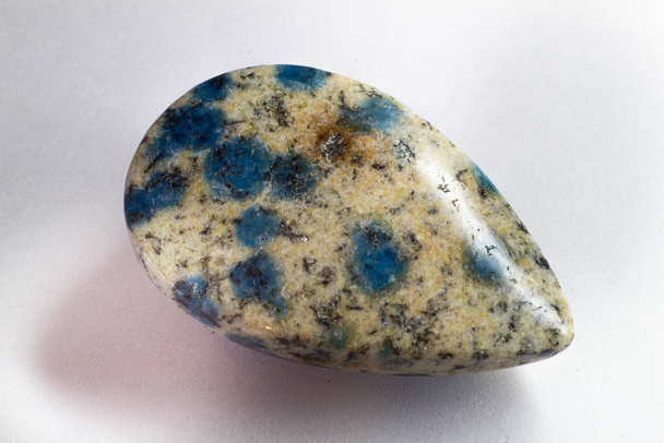 K2 Jasper cabochon lágrima, granito K2, azurite azul gota de chuva na fotografia macro granito branco isolado em uma superfície branca.  - Foto, Imagem