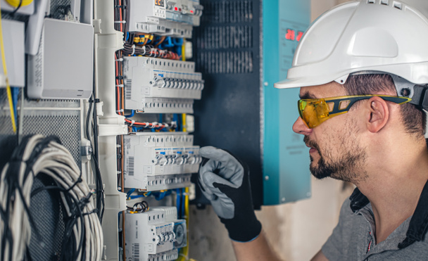 Man, an electrical technician working in a switchboard with fuses. Installation and connection of electrical equipment. - Φωτογραφία, εικόνα