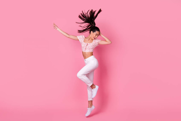 Full body profile photo of sweet young brunette lady jump wear crop top jeans shoes isolated on pink background. - Foto, immagini