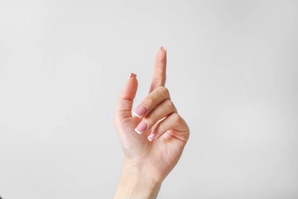 Γυναικείο χέρι με ένα δάχτυλο πάνω σε λευκό φόντο - Φωτογραφία, εικόνα