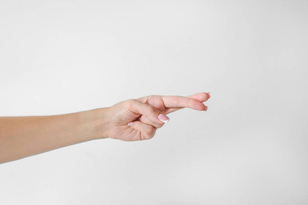 Το χέρι της γυναίκας κρατά τα δάχτυλα σταυρωμένα σε λευκό φόντο - Φωτογραφία, εικόνα