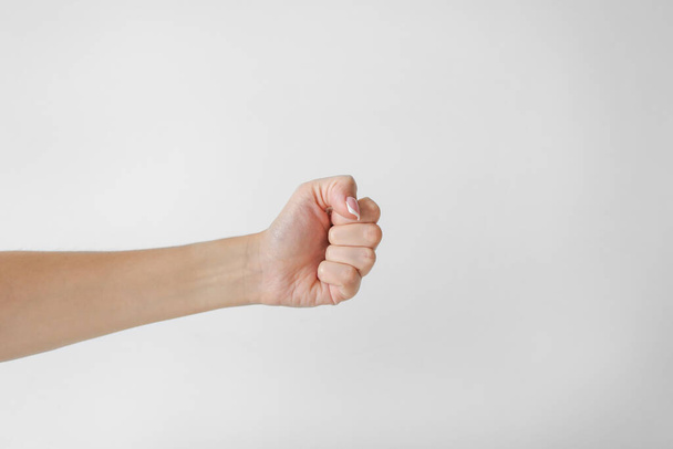 Female hand holds a fist on a white background - Photo, Image