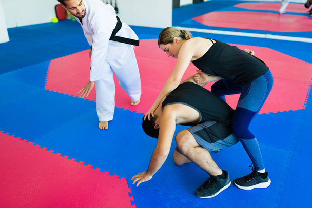 Martial arts coach training with young adults during a personal defense class - Photo, image