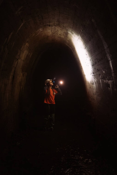 Une jeune femme creuseuse avec une lampe de poche explore le tunnel - Photo, image