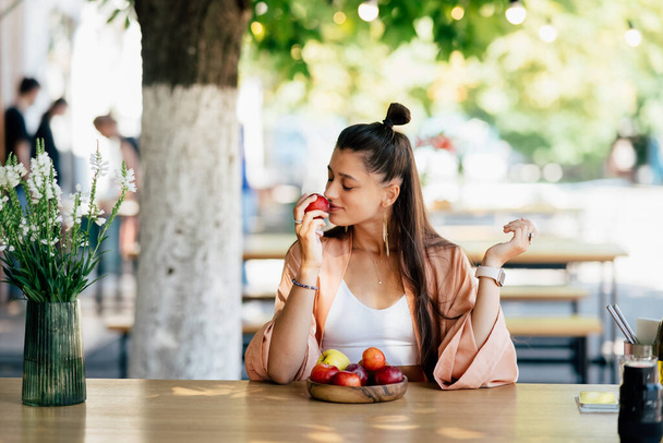 Jonge mooie glimlachende hipster vrouw zitten in veranda cafe in de straat. - Foto, afbeelding