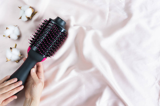 Secador de pelo eléctrico con cepillo reventador sobre fondo rosa - Foto, imagen