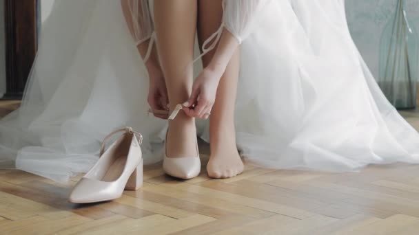 невеста надевает туфли в день свадьбы. Белая туфля на хрупкой ноге девушки - Кадры, видео