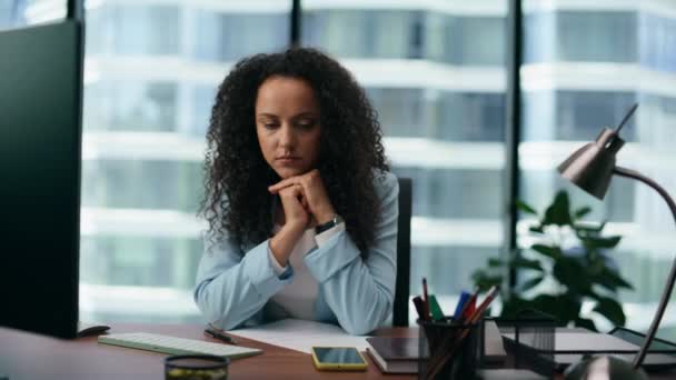 Přepracovaná žena se cítí unaveně, když pracuje zblízka ve firemní kanceláři. Latinskoamerická kudrnatá dívka sedící na pracovišti trpící bolestí hlavy držící hlavu rukama. Nespokojený koncept pracovníka. - Záběry, video