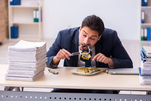 Junge männliche Angestellte isst Wecker - Foto, Bild