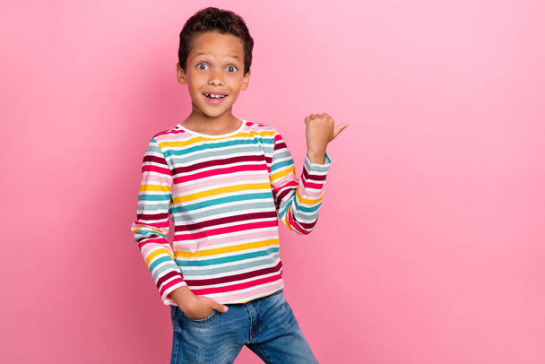 Photo portrait of handsome small hispanic boy impressed point empty space wear stylish striped garment isolated on pink color background. - Zdjęcie, obraz