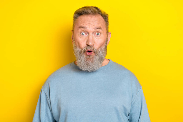 Photo of excited shocked retired guy wear blue sweater big eyes isolated yellow color background. - Photo, image