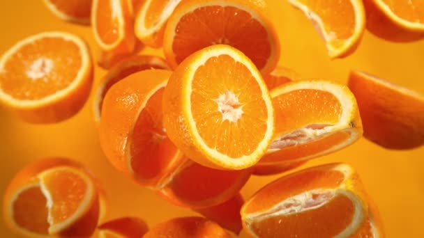Super Slow Motion Shot of Flying Fresh Orange Slices Towards Camera on Orange Background at 1000fps (en inglés). Filmado con cámara de cine de alta velocidad a 4K. - Imágenes, Vídeo