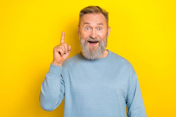 Photo of shocked impressed retired guy wear blue sweater pointing finger up isolated yellow color background. - Photo, image