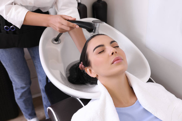 Professional hairdresser washing woman's hair in beauty salon, closeup - Foto, afbeelding