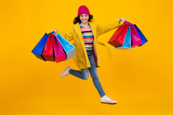 Podzimní výprodej. Dospívající dívka po nakupování. Nákupy, černý pátek, slevy a koncept prodeje. Utíkej a skoč. Šťastný teenager, pozitivní a usměvavé emoce dospívající dívky - Fotografie, Obrázek