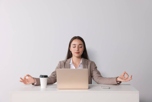 Find zen. Woman taking break from work at table near white wall - Fotó, kép