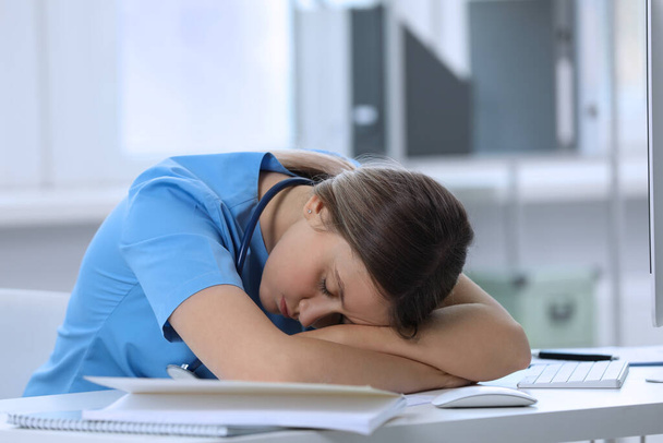 Exhausted doctor sleeping at workplace in hospital - Фото, зображення