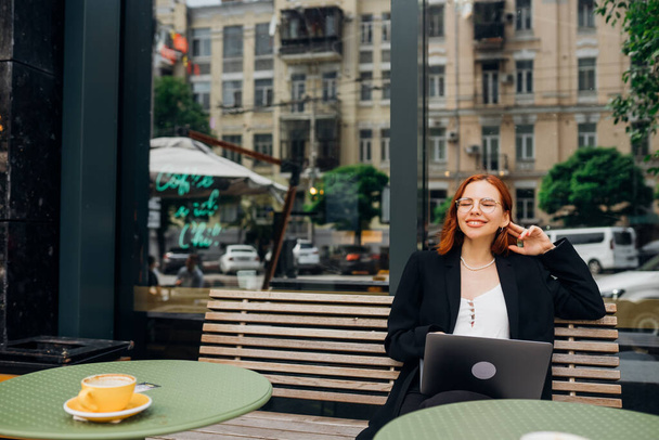 Bella donna rossa che lavora sul computer portatile al caffè all'aperto - Foto, immagini